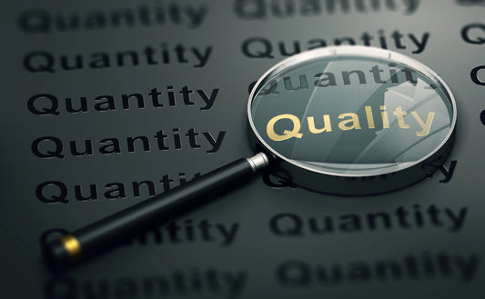 magnifying glass finding the word quality amongst quantity