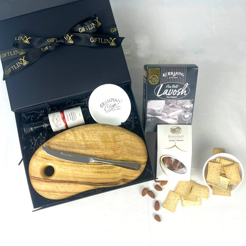 Gift set with a wooden cutting board, knife, and assorted snacks on a white background