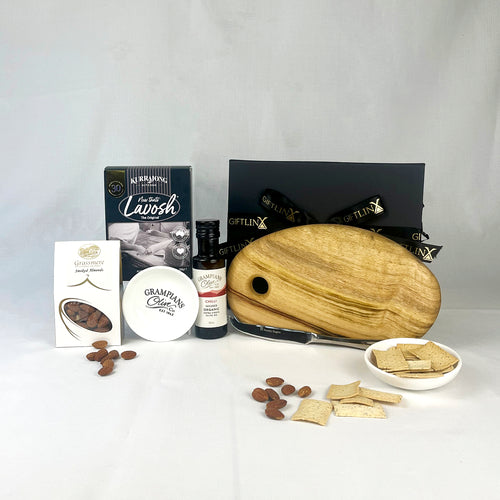 Assorted snacks and items including a wooden cutting board, crackers, and a bottle of sauce on a white background.