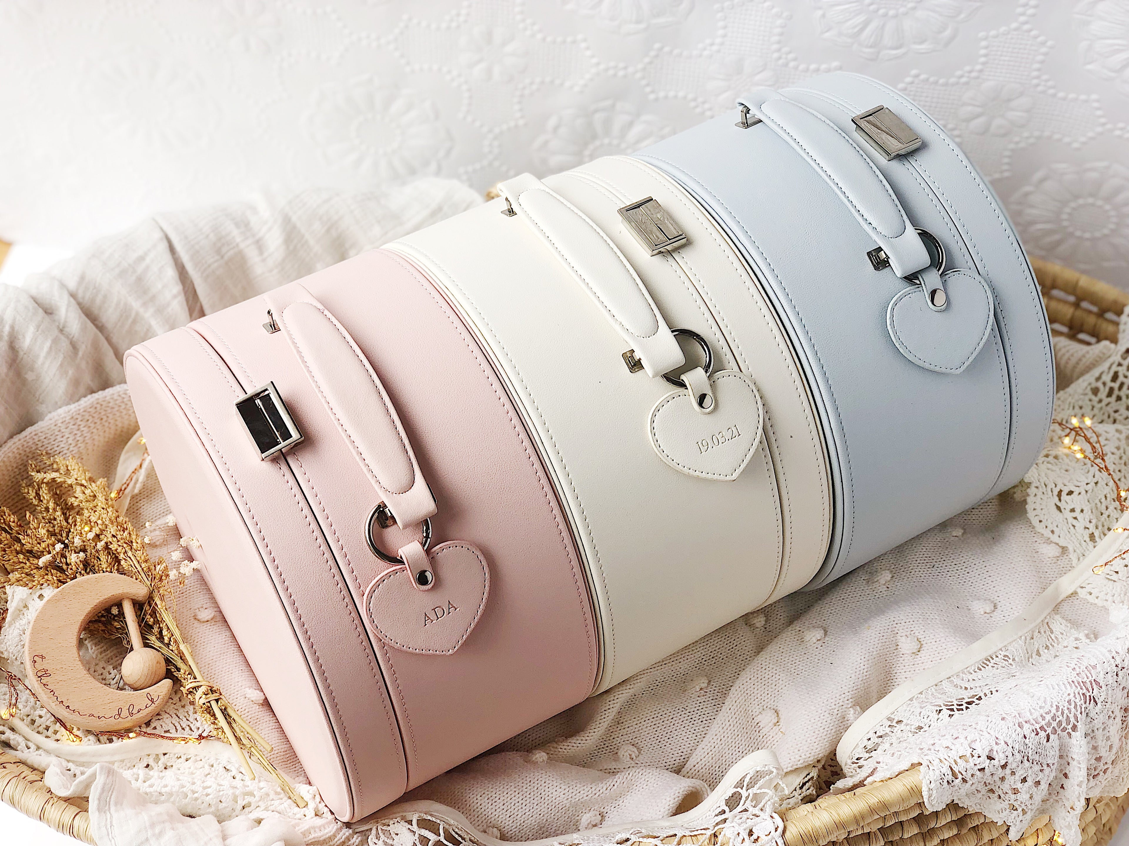 three baby keepsake suitcases lined up on a baby blanket inside a moses basket