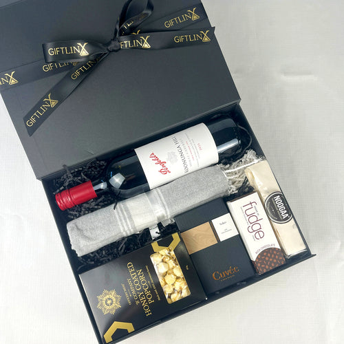 Gift box with wine, popcorn, and fudge on a white background