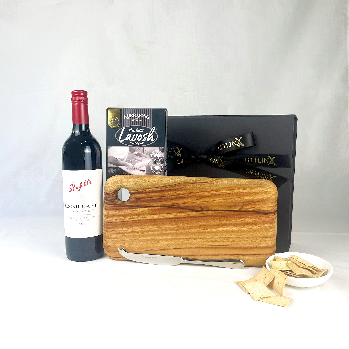 Wine bottle, cheese board, knife, and crackers on a white background