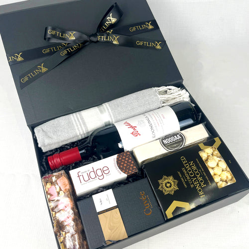 Gift box with wine, fudge, and chocolate on a white background