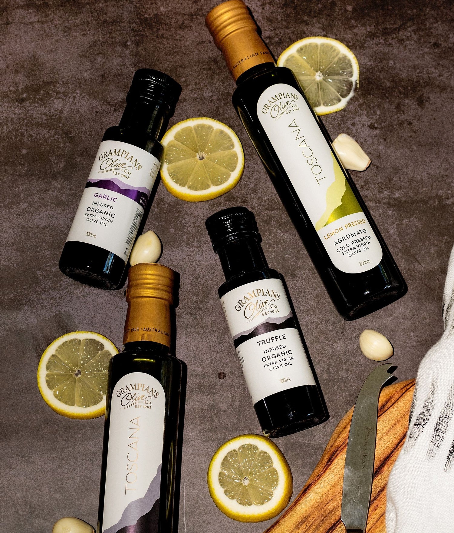 Selection of organic infused olive oils including garlic oil, truffle oil and lemon oil set on table with fresh garlic and lemon slices..