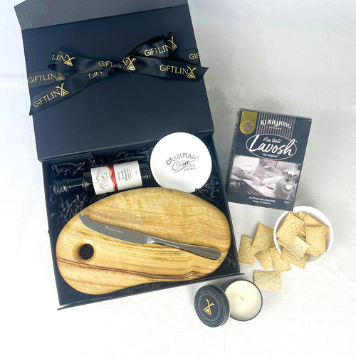 Gift set with a wooden cutting board, knife, and other items on a white background