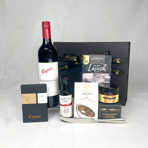 Gourmet gift set with wine, chocolate, and other snacks on a white background