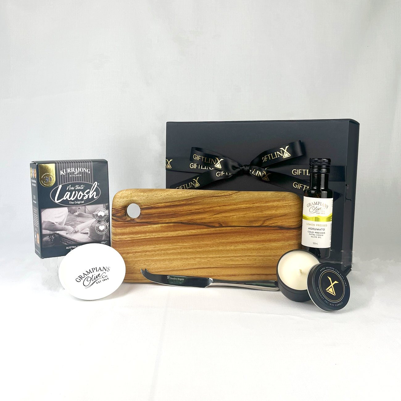 Gift set with a wooden cutting board, a bottle of olive oil, and other items on a white background.
