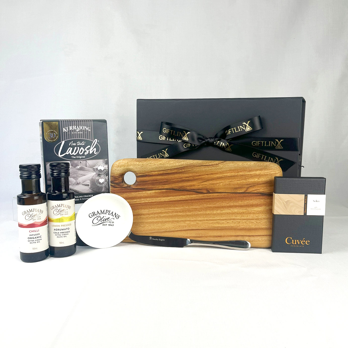 Gourmet gift set with a wooden cutting board, bottles, and a box on a white background