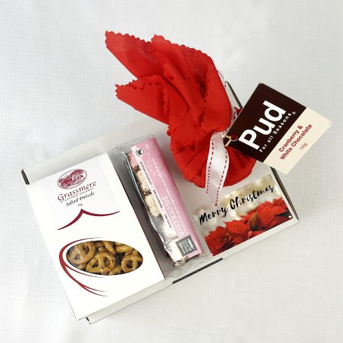 Gift box with pretzels, rocky road and Pud Christmas pudding in red fabric on a white background