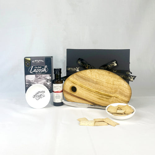 Gourmet gift set with a wooden board, cheese, and other items on a white background