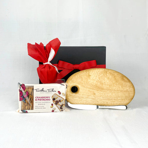 wooden cheese board with knife, Christmas pudding and crispbread with gift box with red ribbon on white background