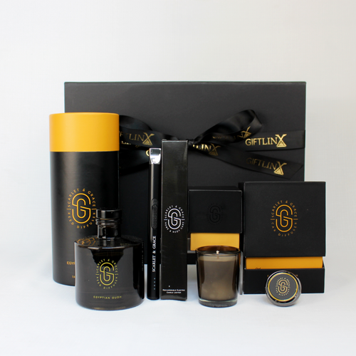 black gift box standing behind a home diffuser, candle, car diffuser and electronic candle lighter all in black and gold boxes