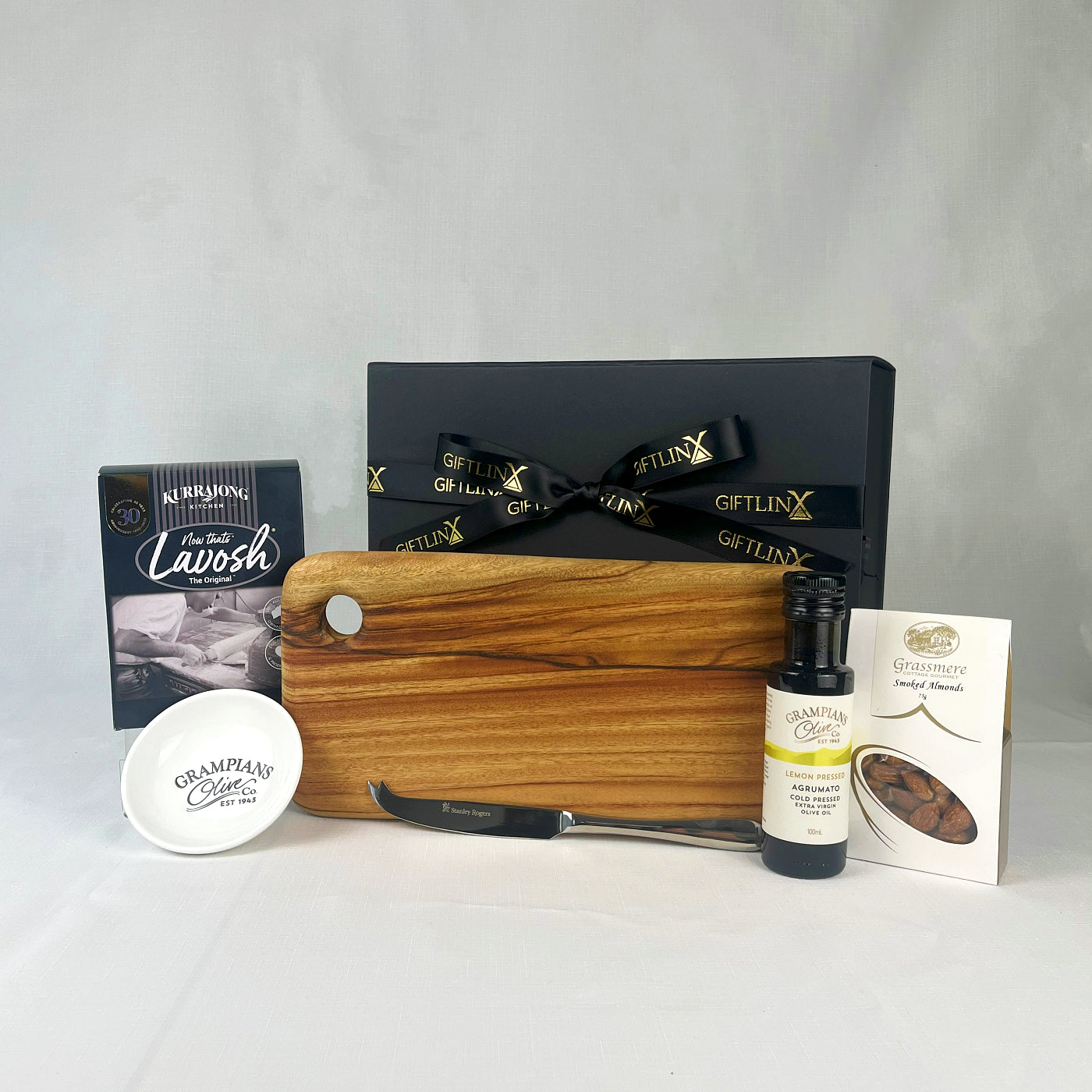 Gift set with wooden cutting board, knife, and other items on a white background