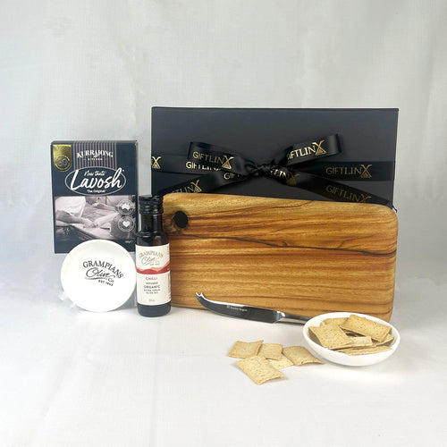 Gift set with a wooden cutting board, cheese, and other items on a white background