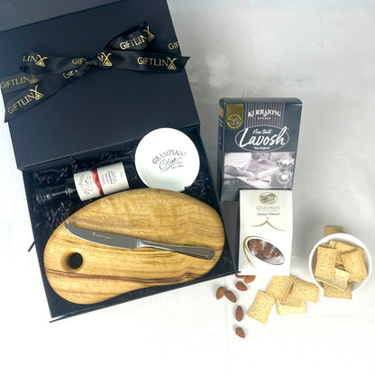 Gift set with a wooden cutting board, knife, and assorted snacks on a white background