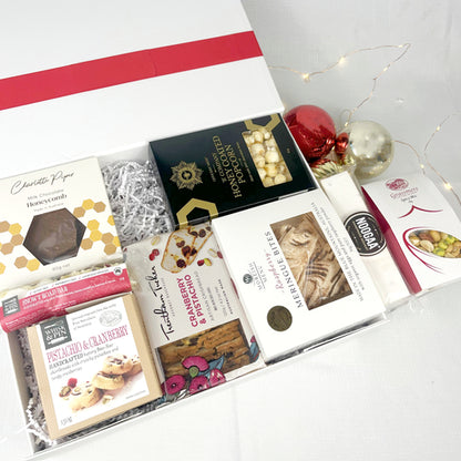 Assorted chocolate bars and treats in a box with red ribbons on a white surface