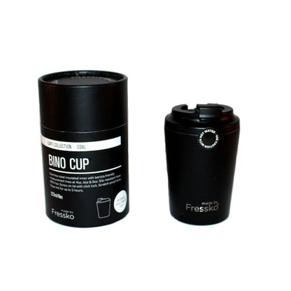 Black reusable travel mug next to black cylinder packaging on white background