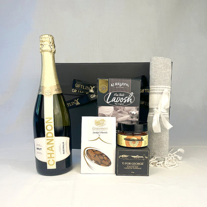 Gift basket with Chandon champagne, Lavosh crackers, and other items on a gray background