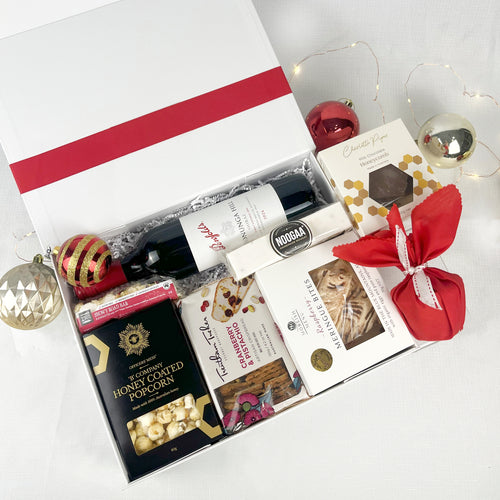 Gift box with wine, snacks, and a Christmas Pudding on a white background