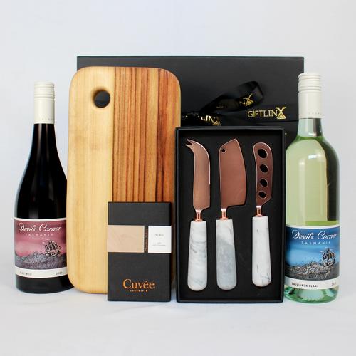 Black gift box with a duo of red and white white standing next to a medium timber serving board, marble and brass cheese knife set in black gift box and a block of premium chocolate