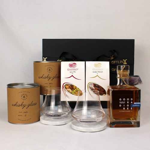 black gift box standing behind a bottle of Goodradigbee Whisky, two handblown whisky glasses on marble coasters and some bar snacks