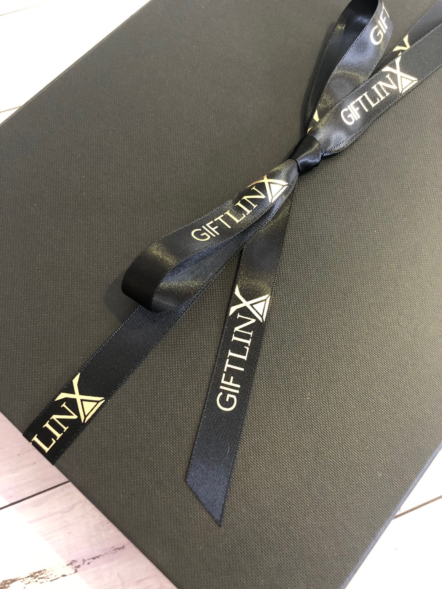Branded ribbon tied in a bow on a luxury black gift box.