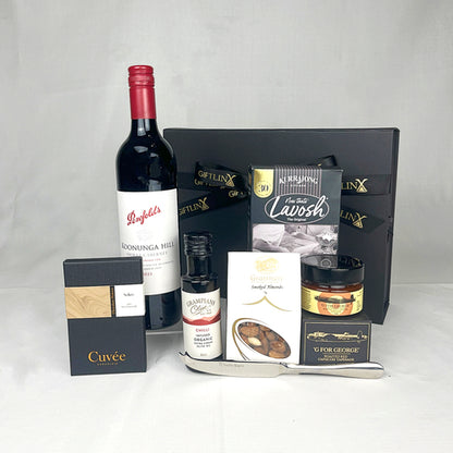 Gourmet gift set with wine, chocolate, and other snacks on a white background