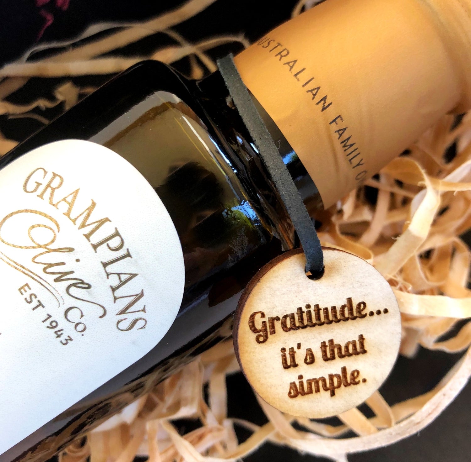 Laser engraved Timber swing tag with quote "Gratitude... it's that simple!" hanging on the neck of a bottle of infused oil to display your brand on your gifts.