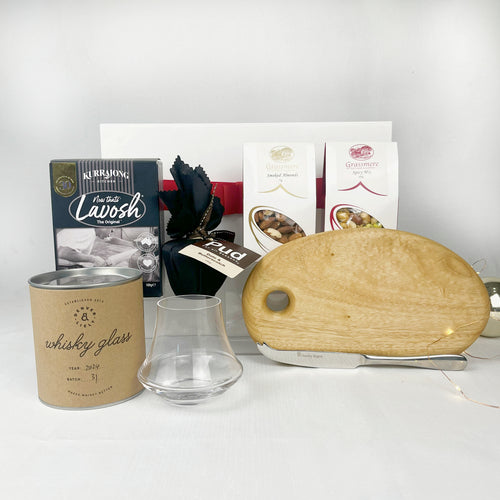 Collection of items including a wooden cutting board, glass, and Christmas pudding on a white surface.