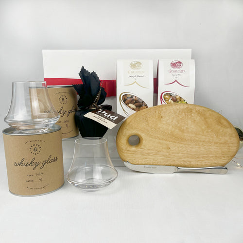 Set of glassware and a wooden cutting board on a white surface with a neutral background