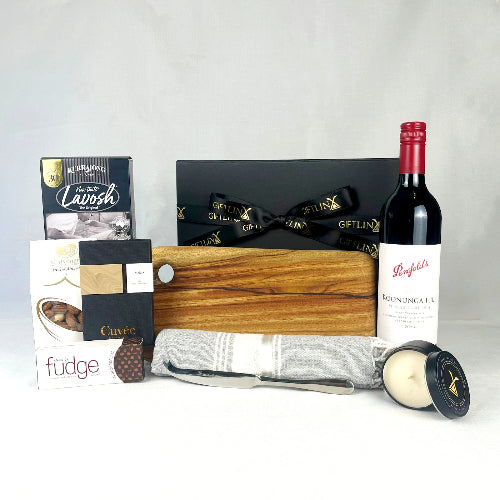 Gift basket with wine, cheese, and other items on a white background