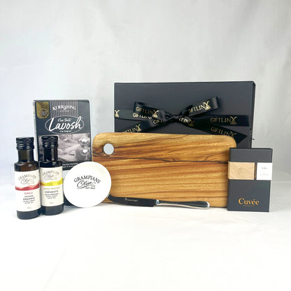 Gourmet gift set with a wooden cutting board, bottles, and a box on a white background