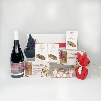 Gift basket with wine, snacks, and Christmas Pudding on a white background