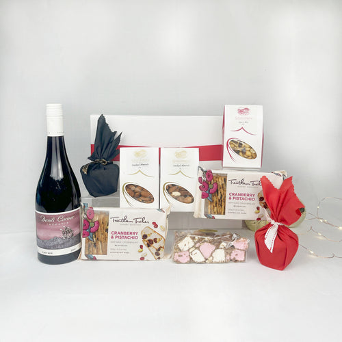 Gift basket with wine, snacks, and Christmas Pudding on a white background