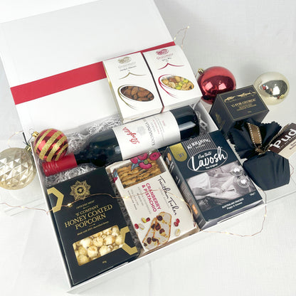 Gift basket with wine, popcorn, and snacks on a white background