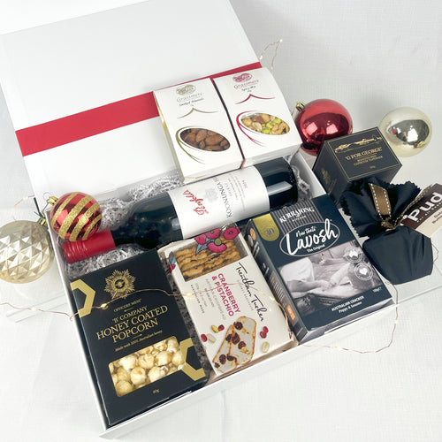 Gift basket with wine, popcorn, and snacks on a white background