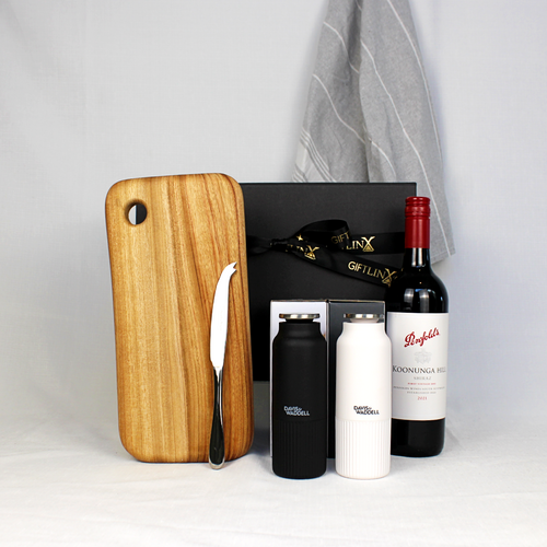 Black gift box with gold ribbon surrounded by a bottle of Australian wine a black and white salt and pepper mill pair, handmade cheese board with stainless steel cheese knife and a 100% cotton hand towel