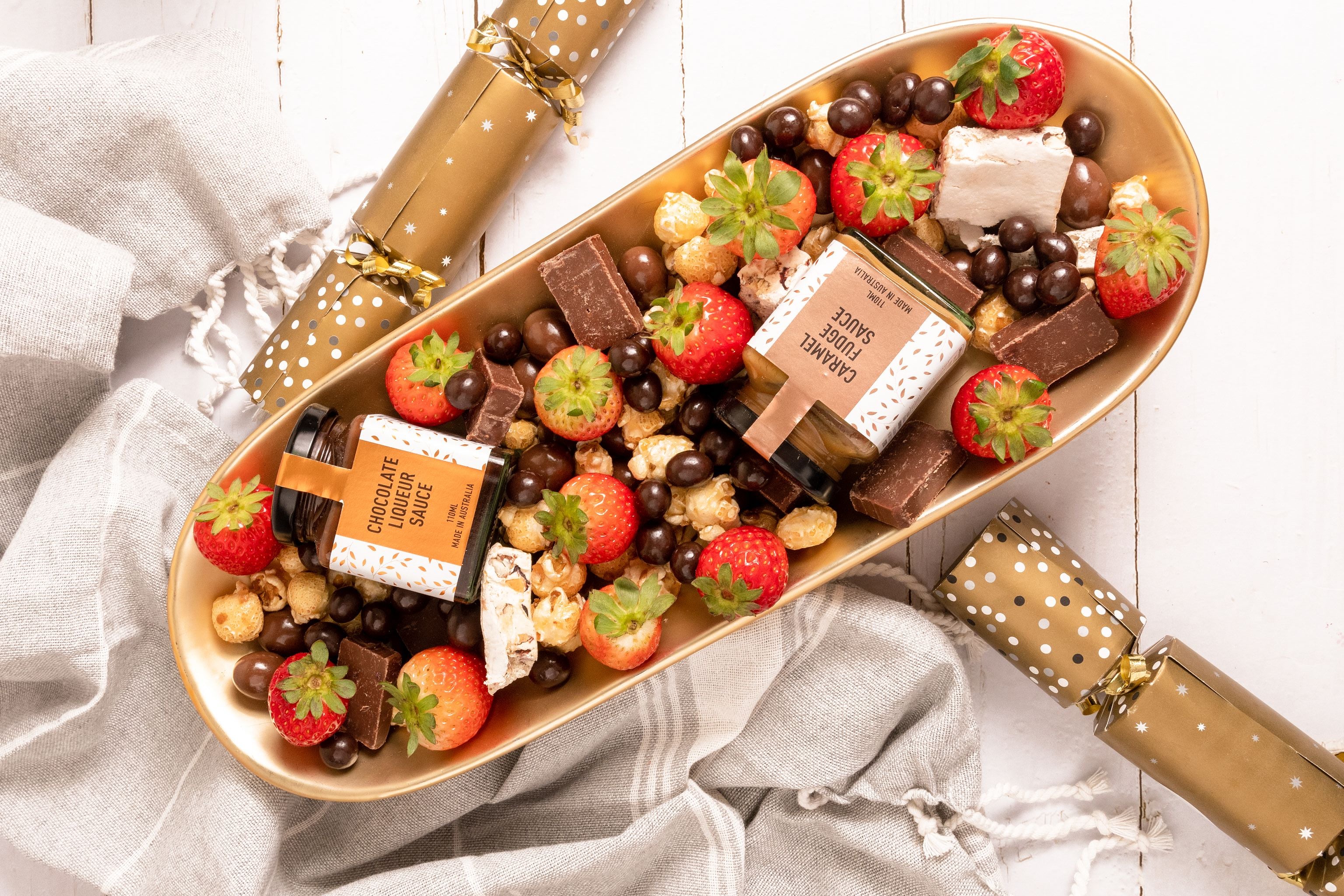 Gourmet chocolate spread with strawberries and nuts on a decorative tray with crackers.