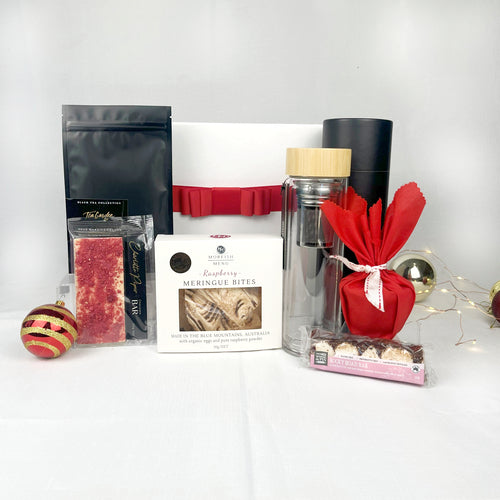 glass double walled tea flask with tea and sweet treats plus a Christmas pudding with white gift box and red ribbon
