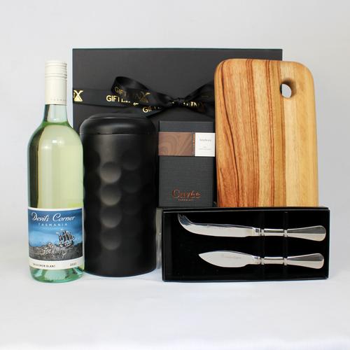 black gift  box standing behind a bottle of Sauvignon Blanc and a stainless steel wine cooler next to a timber serving board, cheese knife set in black box and block of chocolate