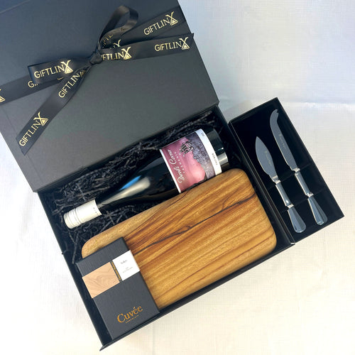 Gift set with wooden cutting board, knives, and bottle in a black 'GIFTLINX' box.