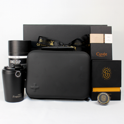 black gift  box standing behind a black moulded first aid kit, travel mug, chocolate and a care diffuser with black and gold box