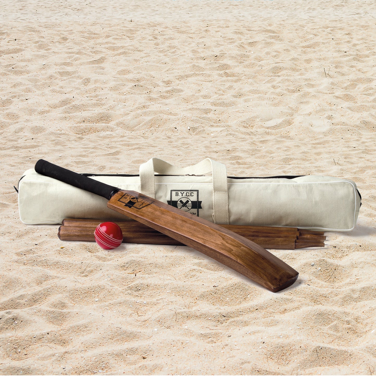 lifestyle photograph of timber cricket set and canvas carry bag on the sand at the beach