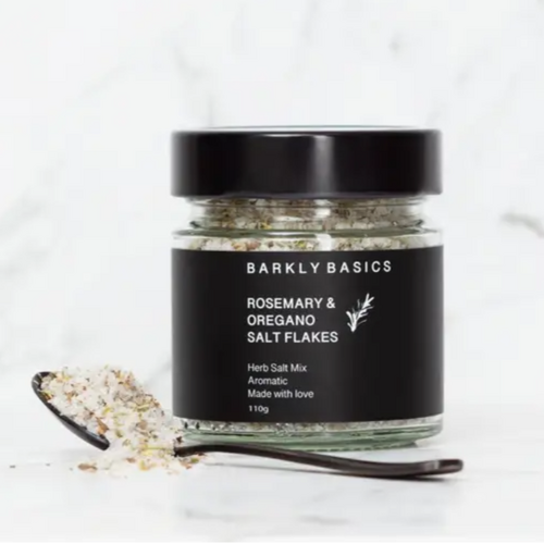 rosemary and oregano salt flakes in a glass jar with black label and lid