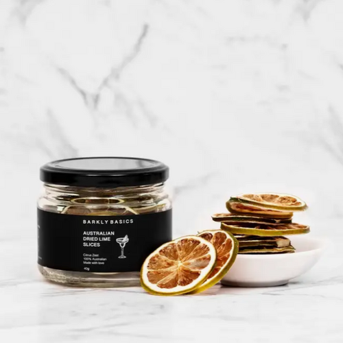 glass jar with black label and lid next to stack of dried lime slices in a white dish