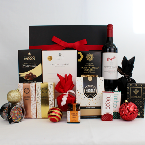 black gift box standing behind a huge selection of products including Australian red wine, Christmas pudding wrapped in black and red fabric, handmade chocolates, fudge, nougat, honey coated popcorn, chocolate coated almonds, butter shortbread and lavosh shards