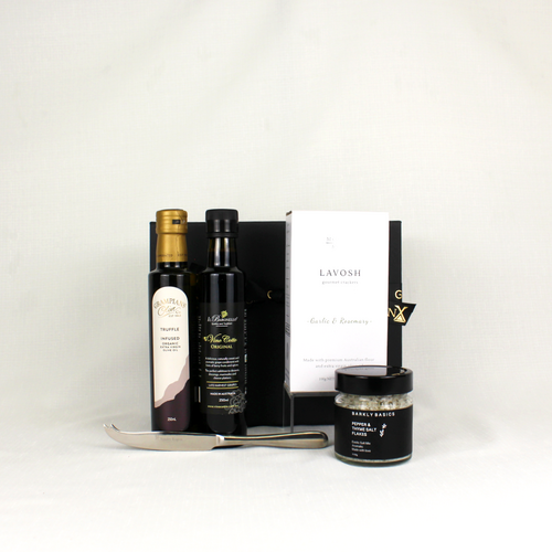 black gift  box with ribbon with bottles of infused olive oil, vino cotto and salt flakes and a cheese knife.