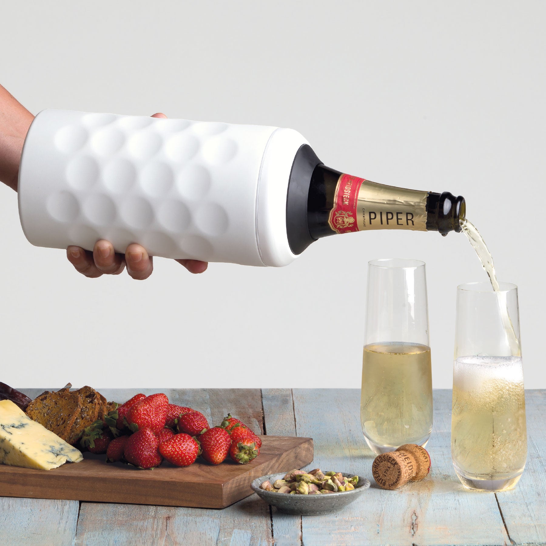 white stainless steel wine cooler with a bottle of champagne being poured into two glasses