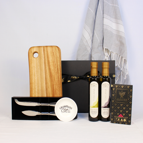 Luxury black gift box with ribbon filled with Australian handmade cheese board with cheese knife set, 2 x infused olive oils with dipping bowl, Australian handmade chocolate bar and a 100% cotton hand towel.