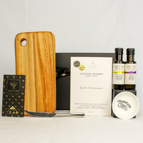 handmade timber cheese board with 2x bottle of infused olive oil and dipping bowl, single stainless steel cheese knife, lavosh shards and premium Australian chocolate bar in a black and gold gift box